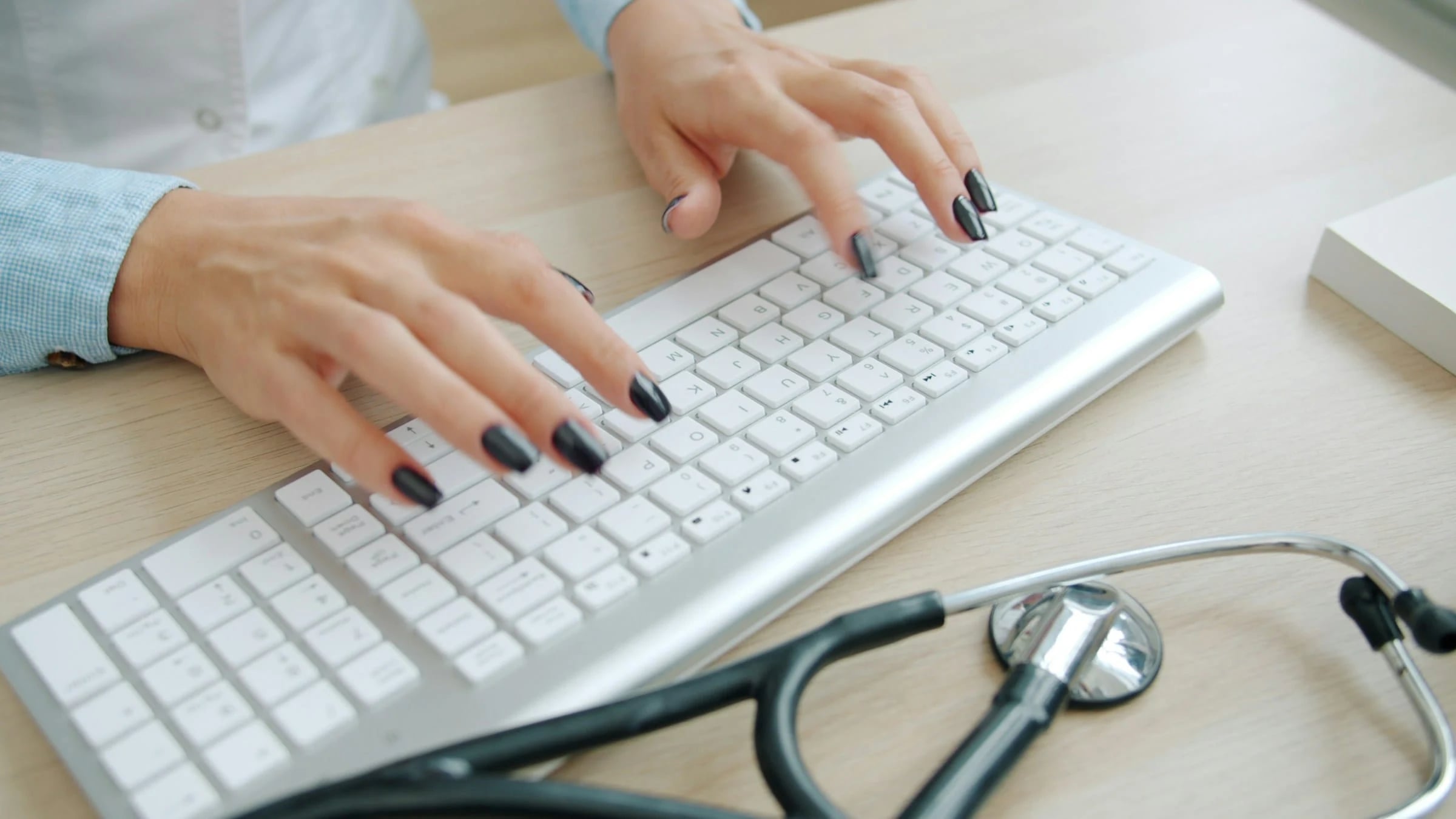 Doctor typing on a keyboard with a stethoscope nearby
