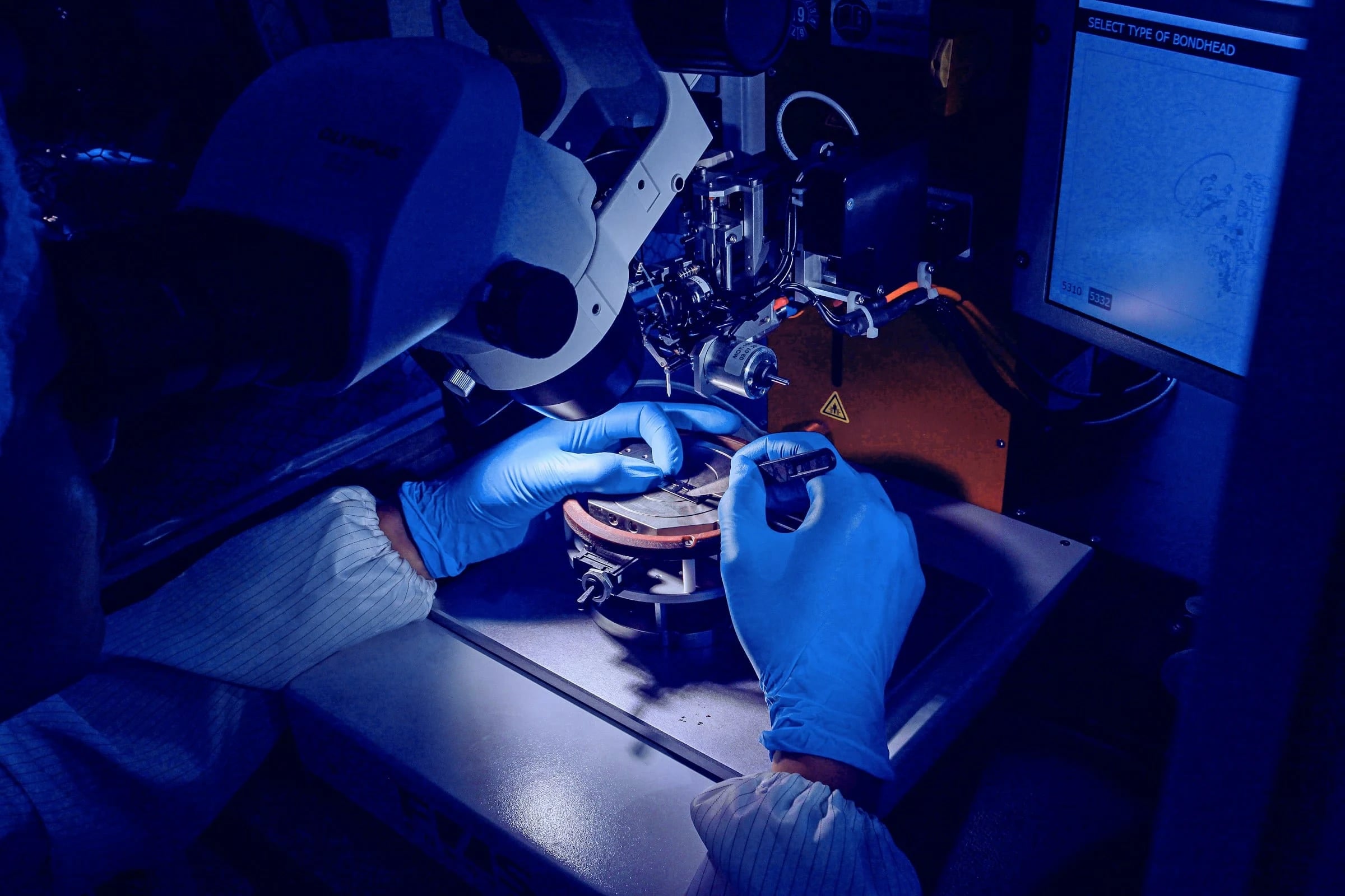 Technician in blue gloves operating a dental lab machine